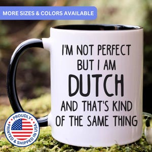 May include: A white ceramic mug with a black interior and handle. The mug features black text that reads: I'M NOT PERFECT BUT I AM DUTCH AND THAT'S KIND OF THE SAME THING. A circular blue, white, and red logo with the text PROUDLY PRINTED & SHIPPED IN USA.