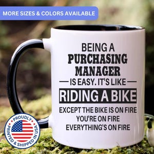 May include: A white ceramic mug with a black interior and handle. The mug features black text that reads: BEING A PURCHASING MANAGER IS EASY. IT'S LIKE RIDING A BIKE EXCEPT THE BIKE IS ON FIRE YOU'RE ON FIRE EVERYTHING'S ON FIRE.
