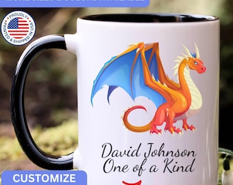 May include: A white ceramic mug with a black handle and interior, featuring a colorful orange and blue dragon illustration. Below the dragon, the text reads David Johnson One of a Kind in black script, with a red arrow pointing toward the text.