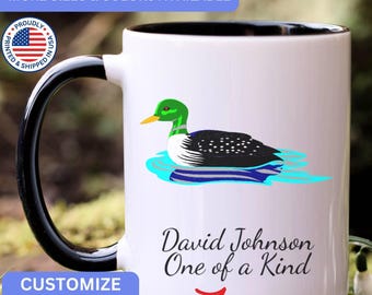May include: A white ceramic mug with a black handle and interior. The mug features a graphic of a mallard duck swimming in blue water. Below the duck, the text reads David Johnson One of a Kind in a black script font with a red arrow underneath.