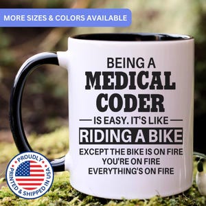 May include: A white ceramic mug with a black interior and handle, featuring the black text: BEING A MEDICAL CODER IS EASY. IT'S LIKE RIDING A BIKE EXCEPT THE BIKE IS ON FIRE YOU'RE ON FIRE EVERYTHING'S ON FIRE. A circular badge with the US flag is included.