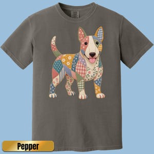 May include: A charcoal gray short-sleeve t-shirt featuring a graphic of a Bull Terrier dog. The dog is designed with a patchwork pattern of various floral, plaid, and polka dot fabrics in shades of pink, blue, yellow, and green. The text Pepper is visible.