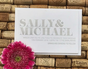 May include: A white wedding invitation card with gray text. The card reads "Sally & Michael" in large, bold letters. The text below reads "Would love you to join them to celebrate their wedding 17th February 2018, 1.30pm, The Tythe Barn, Anyho Drinks and Dancing to Follow."