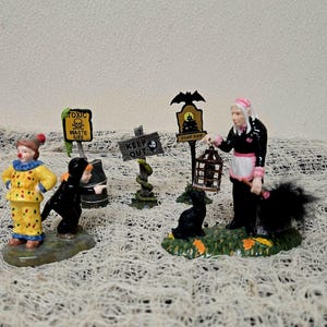 Peut inclure: Un ensemble de figurines miniatures d'Halloween comprenant un clown jaune, un personnage v&ecirc;tu de noir, un panneau de d&eacute;chets toxiques, un panneau keep out avec un serpent, un panneau dead end avec une chauve-souris et une figurine en noir et rose.