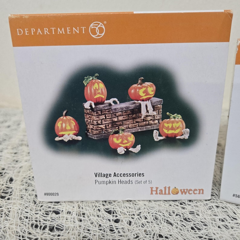Peut inclure: Un ensemble d'accessoires de village Department 56 comprenant cinq t&ecirc;tes de citrouille orange avec des visages jaunes sculpt&eacute;s et des mains et pieds squelettiques blancs. L'ensemble inclut un mur en briques, pr&eacute;sent&eacute; sur une bo&icirc;te blanche.