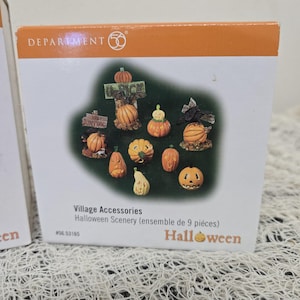 Peut inclure: Un coffret Department 56 Village Accessories Halloween Scenery contenant neuf figurines miniatures de citrouilles, incluant des citrouilles sculpt&eacute;es, un panneau U-PICK, un corbeau sur une citrouille et une chauve-souris sur une bo&icirc;te en carton.