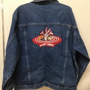 May include: A blue denim jacket with a red and white Looney Tunes patch on the back. The patch features Bugs Bunny, Daffy Duck, Tweety Bird, and Sylvester the Cat.