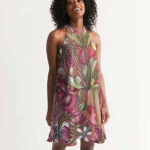 Può includere: Un abito senza maniche con scollo halter su sfondo marrone e stampa floreale con fiori rosa, verdi e bianchi. L'abito ha una vestibilità ampia e una gonna fluida.