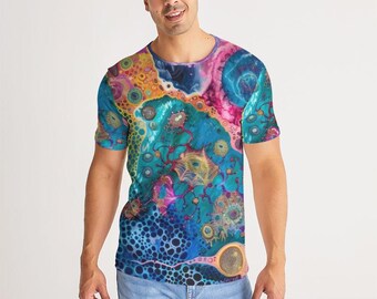 May include: A short-sleeved t-shirt with a vibrant, abstract design. The shirt features a mix of colors, including blue, pink, yellow, and orange, creating a dynamic and eye-catching pattern. The design appears to be a close-up of a cell structure.