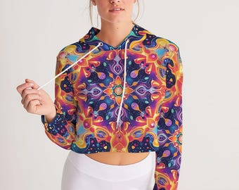 May include: A cropped hoodie with a vibrant, kaleidoscopic pattern in shades of purple, orange, yellow, and blue. The long-sleeved top features a drawstring hood and a fitted silhouette. The design is symmetrical and detailed.