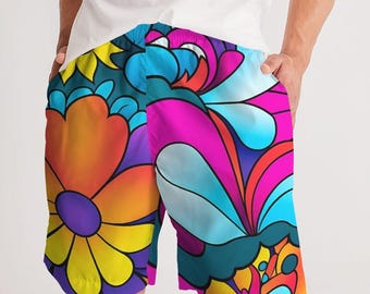 May include: Vibrant, colorful shorts with a psychedelic floral pattern. The design features large flowers and swirling shapes in shades of yellow, orange, purple, pink, and blue. The shorts have a drawstring waistband.