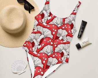 May include: A red and white one-piece swimsuit with a mushroom print. The swimsuit has a scoop neck and thin straps.