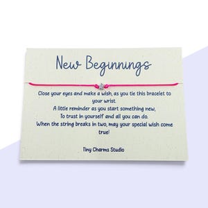 Könnte beinhalten: Ein leuchtend pinkfarbenes Schnurarmband mit einem kleinen silbernen Sternanhänger, befestigt an einer cremefarbenen Karte mit dem Text New Beginnings, einem Gedicht über das Wünschen und dem Markennamen Tiny Charms Studio in dunkelblauer Schrift.