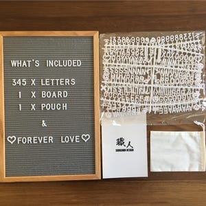 K&ouml;nnte beinhalten: Ein graues Filz-Buchstabenbrett mit Holzrahmen, eine wei&szlig;e Filztasche und ein Blatt mit wei&szlig;en Plastikbuchstaben. Auf dem Brett steht der Text "WHAT'S INCLUDED" und "345 X LETTERS" und "1 X BOARD" und "1 X POUCH" und "& FOREVER LOVE". Die Tasche ist mit "職人" beschriftet.