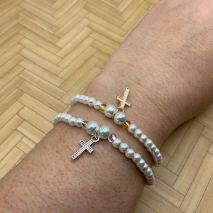 White glass pearl with cross and initial letter stretch bracelets. Silver and golden tone cross charm bracelets. Mother’s Day gift