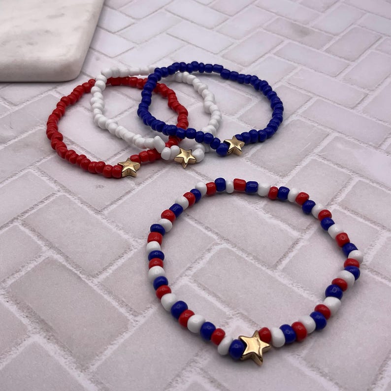 May include: Red, white, and blue beaded bracelets with gold star charms. The bracelets are made of small, round beads and are arranged in a patriotic color scheme. The bracelets are a perfect accessory for any occasion.