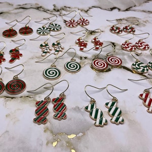 May include: Assortment of gold-tone dangle earrings with red, green, and white candy cane and swirl designs.