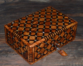 May include: A wooden box with a geometric pattern inlaid with mother of pearl. The box has a keyhole and a small key attached to it.