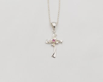 Puede incluir: Un collar de plata con un colgante de cruz con una piedra preciosa rosa.