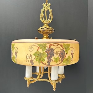 May include: A vintage brass and glass chandelier with a grapevine design. The chandelier has five lights and a round, frosted glass shade with a painted grapevine design.