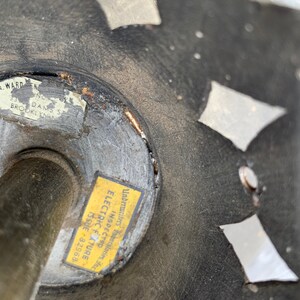 K&ouml;nnte beinhalten: Nahaufnahme einer schwarzen Metallleuchte mit einem dekorativen Design. Ein gelber Aufkleber mit dem Text "Underwriters' Laboratories Inc. Electric Fixture Inspected Issue 82968" ist an der Leuchte angebracht.