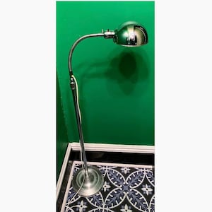 May include: A chrome floor lamp with a flexible arm and a dome-shaped shade. The lamp is on a patterned tile floor.