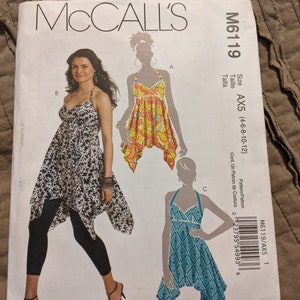 May include: McCall's sewing pattern M6119 for a halter top dress in sizes AX5 (4-6-8-10-12). The pattern shows three different versions of the dress: one in black and white, one in yellow and orange, and one in blue and white.