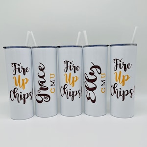 May include: Four white tumblers with black and gold lettering. The tumblers say "Fire Up Chips!" and have the initials "CMU" on them. Two of the tumblers have the names "Grace" and "Elly" written on them.