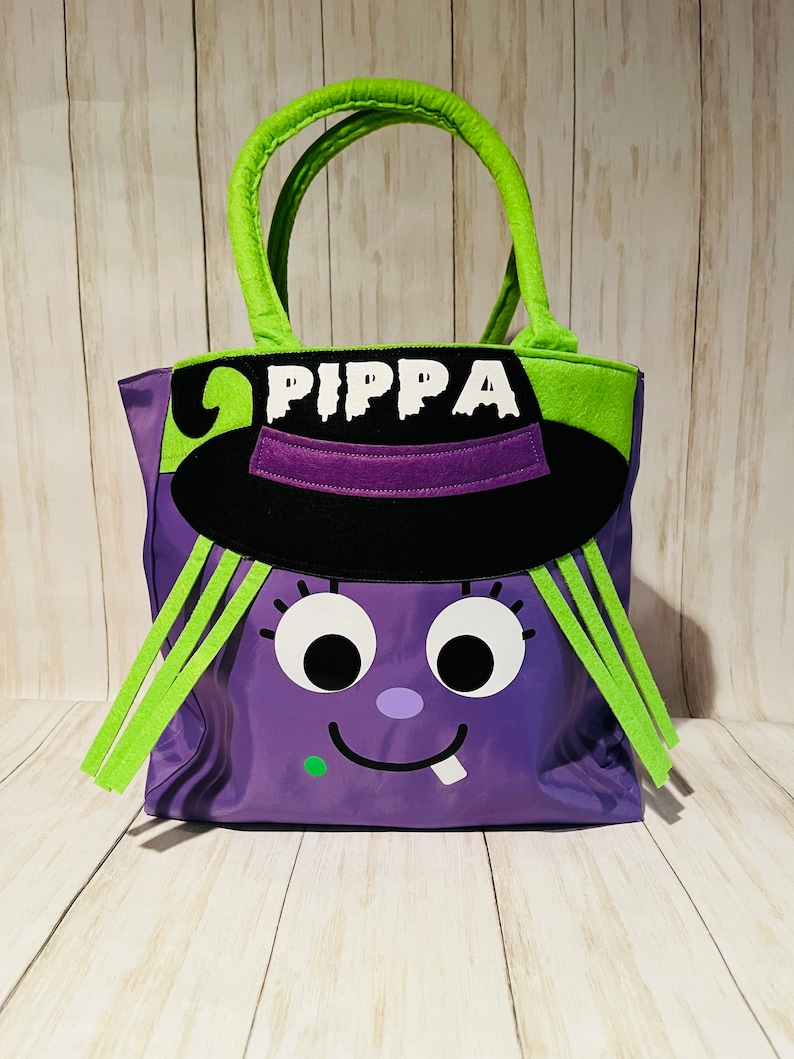 May include: Purple Halloween trick-or-treat bag with a witch face, green hair, and a black hat. The bag has the name "PIPPA" written on it.