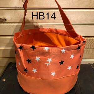 May include: Orange and white star patterned fabric trick or treat bag with black stars. The bag has a fabric handle and the text "HB14" is printed on the handle.