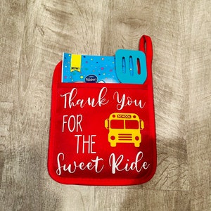 Puede incluir: Manopla de horno roja con un gr&aacute;fico de autob&uacute;s escolar amarillo y el texto "Thank You For The Sweet Ride".