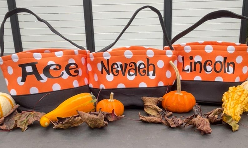 May include: Three orange and black Halloween trick-or-treat bags with white polka dots. The bags are personalized with the names "Ace", "Nevaeh", and "Lincoln".