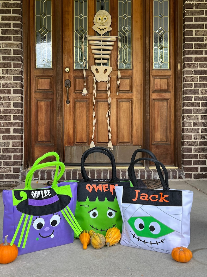 May include: Three Halloween trick-or-treat bags with different character designs. The bags are purple, green, and white with black accents. The bags are labeled "Oaklee", "Owen", and "Jack".