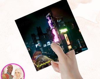 May include: A sticker featuring a cyberpunk cityscape with neon lights and the text "Cyberpunk". The sticker is being held by a hand.