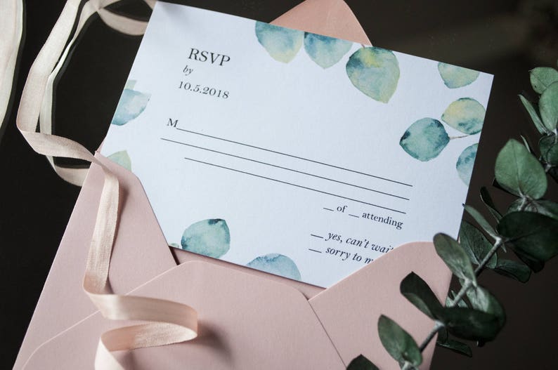 Op de afbeelding: Een witte RSVP-kaart met een aquarelontwerp van groene bladeren. De kaart heeft de tekst "RSVP by 10.5.2018" en een regel voor de naam van de gast.