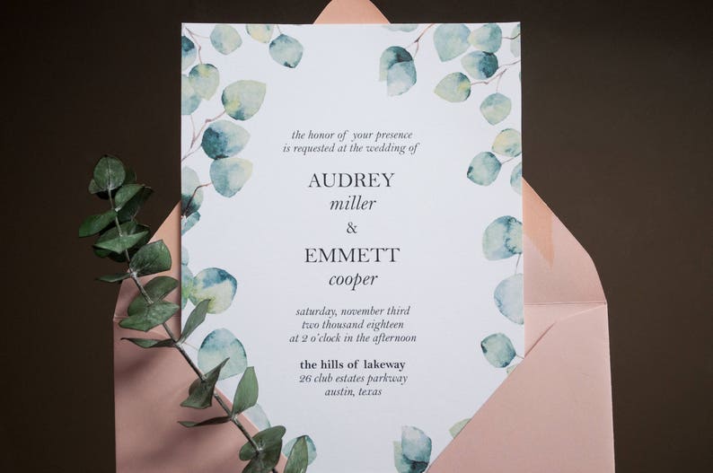 Op de afbeelding: Huwelijksuitnodiging met een witte achtergrond en een aquarelontwerp van eucalyptusbladeren in tinten groen en blauw. De tekst luidt "the honor of your presence is requested at the wedding of Audrey miller & Emmett cooper saturday, november third two thousand eighteen at 2 o'clock in the afternoon the hills of lakeway 26 club estates parkway austin, texas"