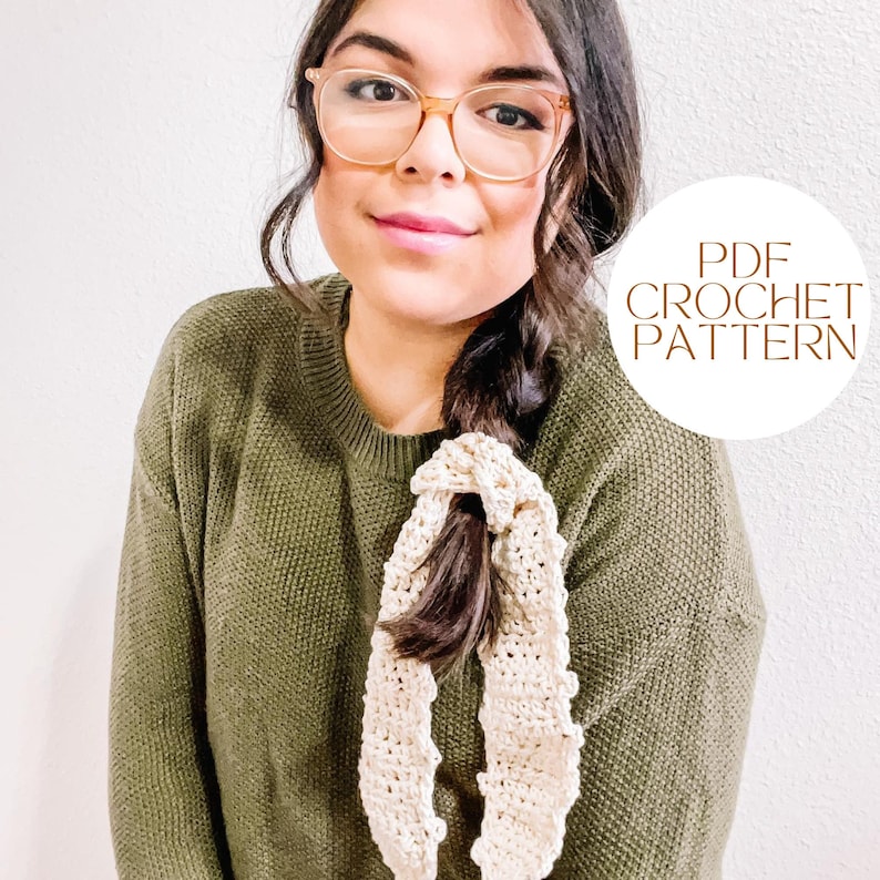 Pode incluir: Uma mulher vestindo um su&eacute;ter verde e &oacute;culos com uma faixa de cabelo de croch&ecirc; amarrada em seu rabo de cavalo. O texto "PDF CROCHET PATTERN" est&aacute; em um c&iacute;rculo no lado direito da imagem.
