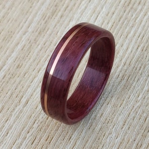 May include: A dark purple wooden ring with two thin copper bands inlaid into the wood.