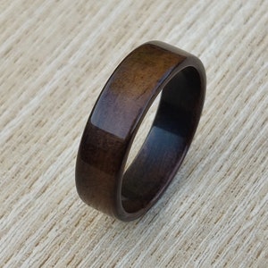 May include: A dark brown wooden ring with a smooth, polished finish.