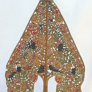 Può includere: Un burattino d'ombra indonesiano tradizionale, o wayang kulit, che rappresenta un albero con uccelli e fiori. Il burattino è fatto di pelle tagliata in modo intricato e dipinto con colori vivaci, tra cui rosso, verde, oro e nero. È montato su un bastone di legno.