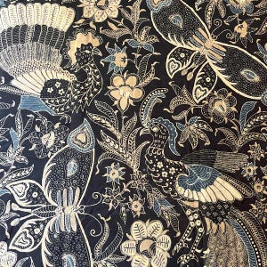 Könnte beinhalten: Schwarzer Stoff mit einem goldenen und blauen Muster aus Pfauen und Schmetterlingen. Der Stoff hat ein traditionelles indonesisches Batik-Design.