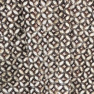Puede incluir: Tela marrón y blanca con un patrón repetitivo de círculos y estrellas entrelazados.