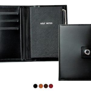 Könnte beinhalten: Schwarzer Leder-Golf-Scorecard-Halter mit Stifthalter, Kartenfach und Klappenverschluss mit Knopf. Der Halter trägt die Aufschrift "GOLF NOTES" auf der Vorderseite.