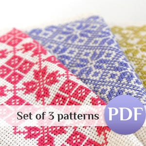 May include: A set of 3 patterns PDF featuring three pieces of white fabric with cross-stitch embroidery. The designs include geometric floral motifs in bright pink, blue, and olive green thread, arranged in a repeating grid pattern.