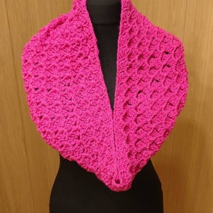 Puede incluir: Un cuello de punto de ganchillo rosa con un patrón de encaje. El cuello se muestra en un maniquí negro.