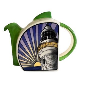 May include: A green and white ceramic teapot featuring a lighthouse design. The teapot has a green spout and handle, and a white body with a blue and purple striped background. The lighthouse is white with gold trim and a black window. The teapot is decorative and not intended for use.