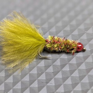 May include: A green and red fly fishing lure with a yellow feather tail.