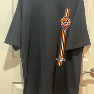 May include: Black t-shirt with a vertical design on the right side. The design includes orange and white stripes, a red and orange graphic, and the word "Dishwalla" in white text.