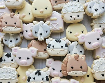 May include: A collection of sugar cookies shaped like farm animals including pigs, cows, sheep, horses, and chicks, alongside barn-shaped cookies. Each cookie features detailed icing in pastel colors with simple, friendly facial expressions.