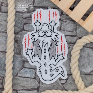 May include: A white sticker with a cartoon illustration of a gray and white cat with red lightning bolts around it. The cat is looking up with a surprised expression and its paws are raised in the air. The text "looking for more? CHOWFEUR.COM" is at the top of the sticker.